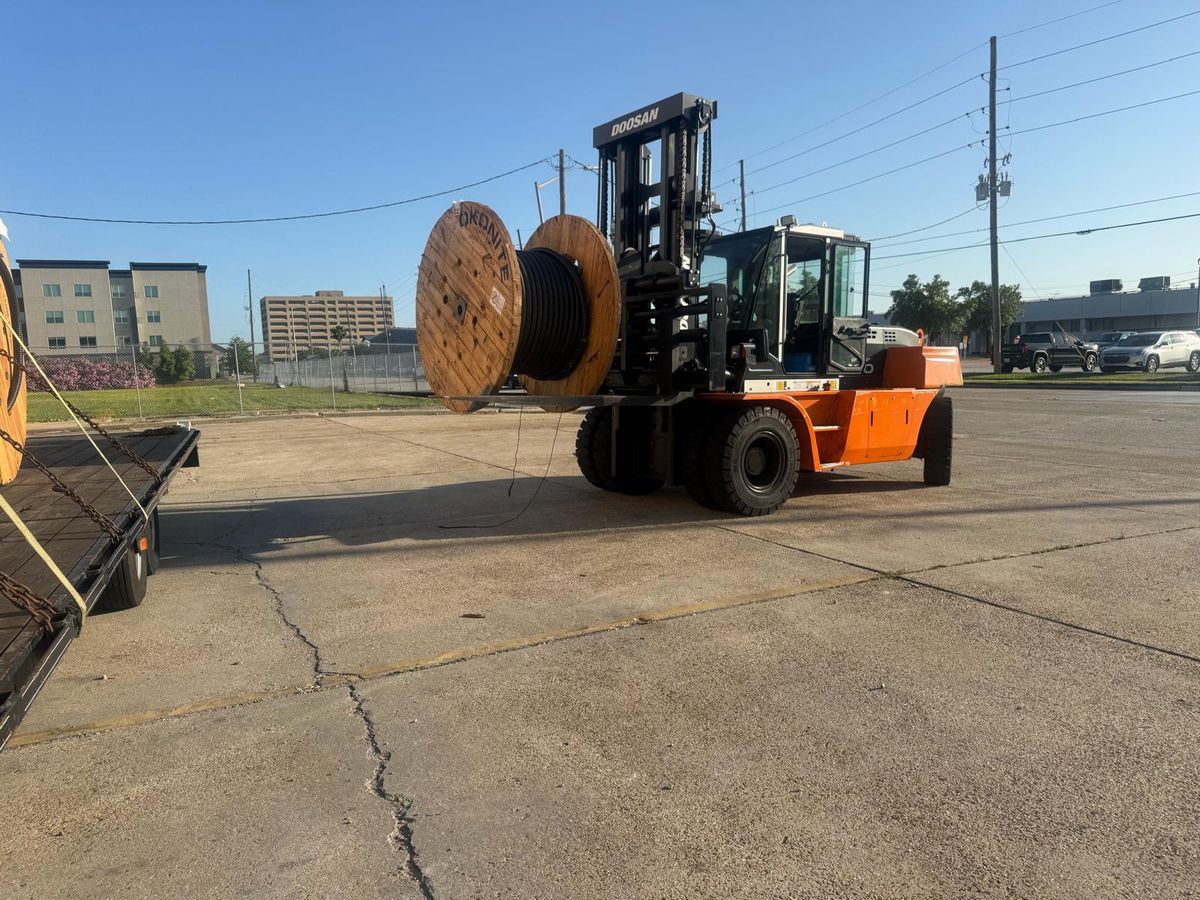 Forklift placing a large cable reel on a trailer